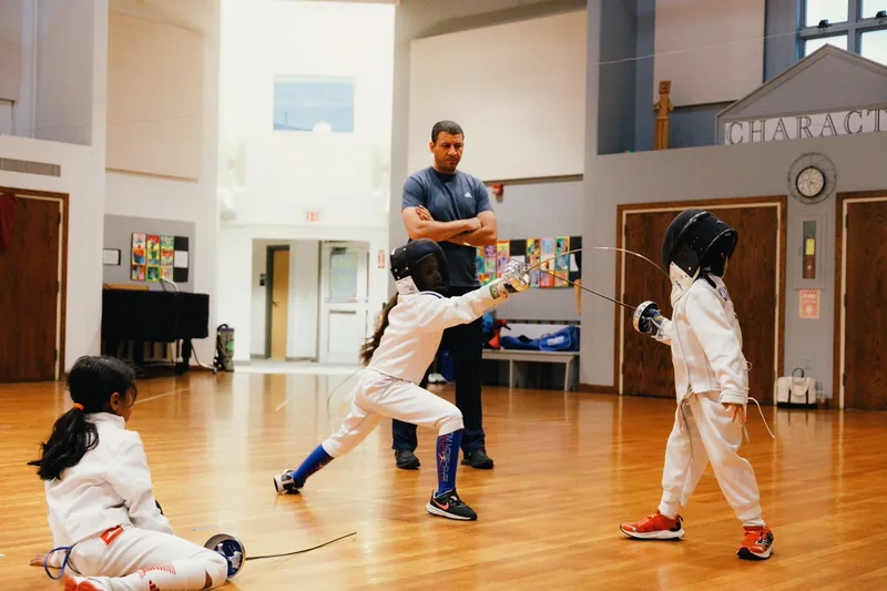 Two saber fencers mid-bout on a strip.